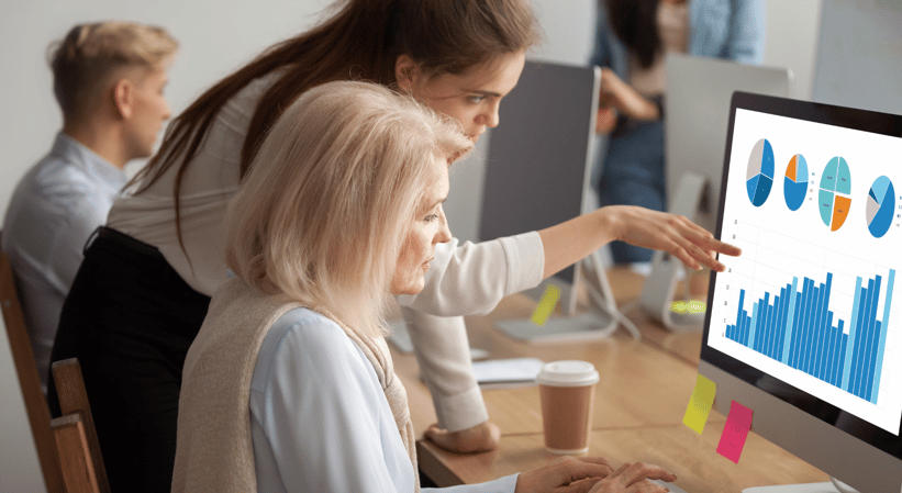 Two women discussing charts on a laptop